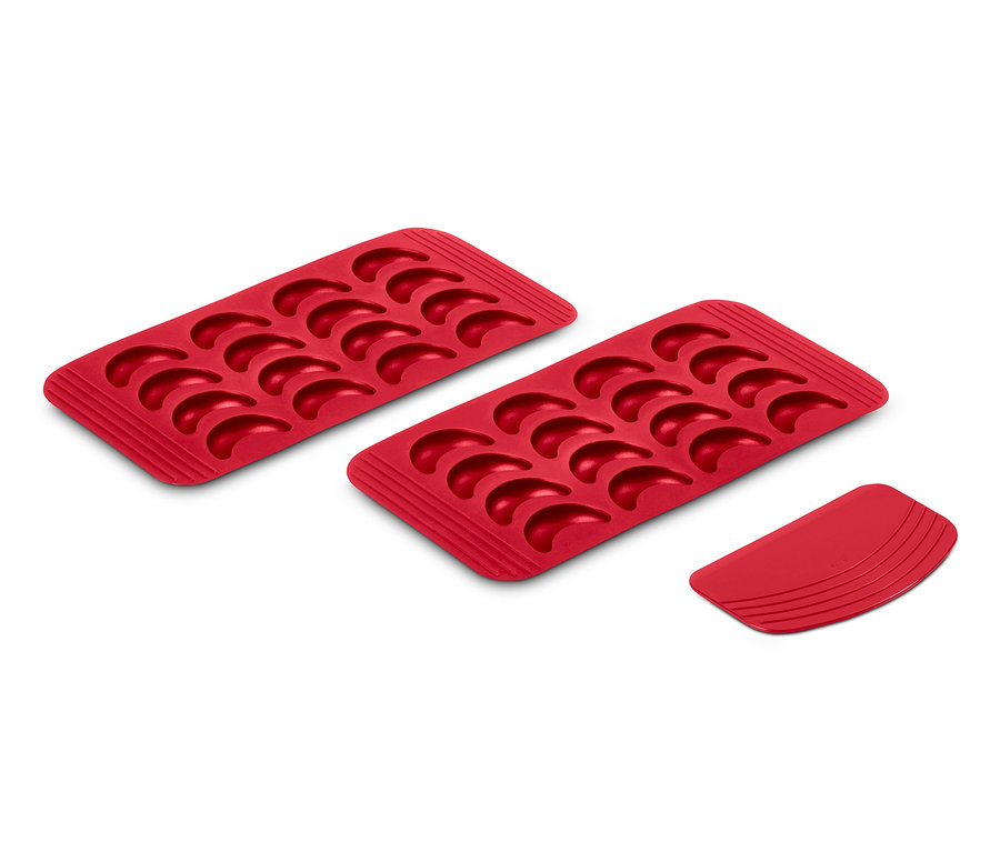 Zwei rote Vanillekipferl-Backmatten und ein roter Teigschaber liegen auf einem weißen Untergrund.