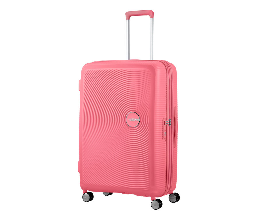 Nahaufnahme eines großen, sonnengeküssten korallenroten American Tourister Hartschalen-Koffers »Soundbox« Spinner.