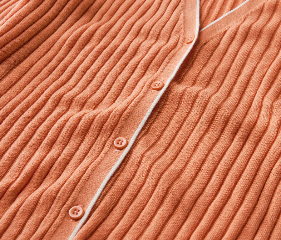 Nahaufnahme eines orangefarbenen Cardigans mit Knöpfen und Seide.