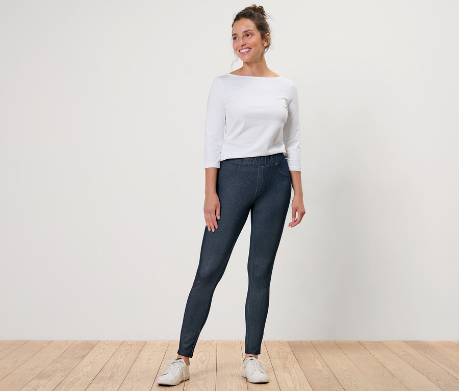 Frau posiert in Leggings in Jeansoptik und weißem Oberteil.