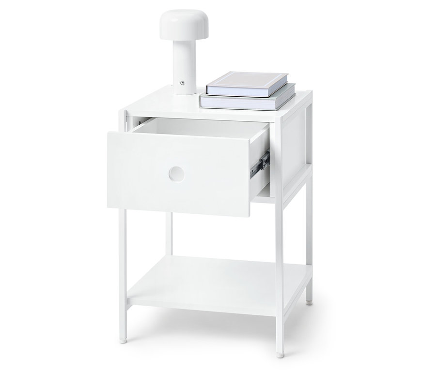 Weißer Nachttisch mit offener Schublade, Lampe und Büchern obenauf.