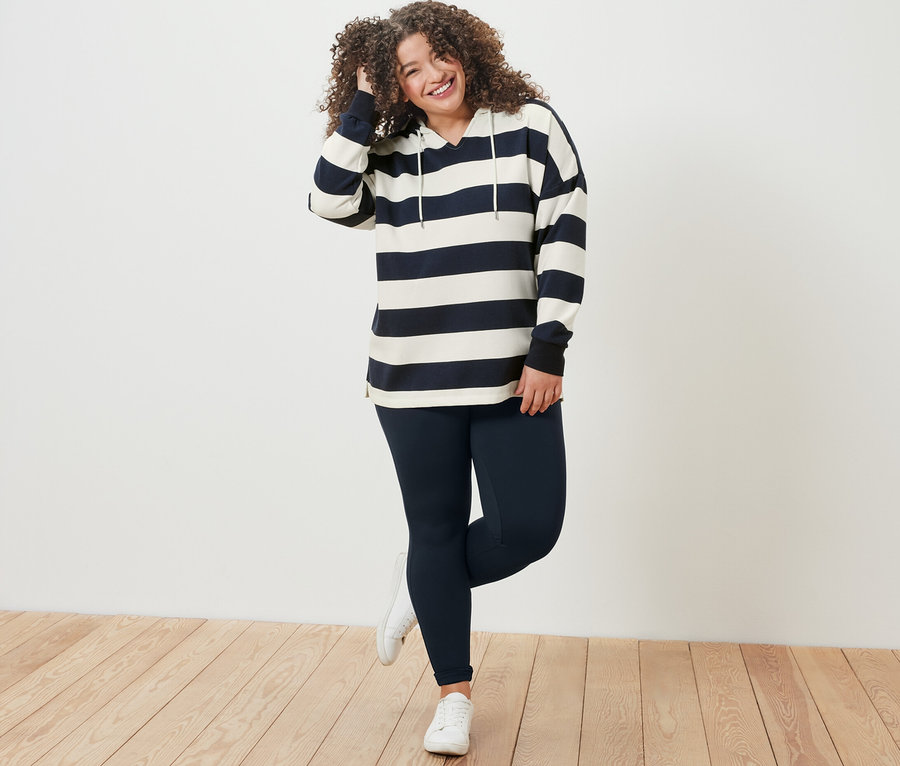 Frau posiert in gestreiftem Hoodie und Heavy-Leggings.