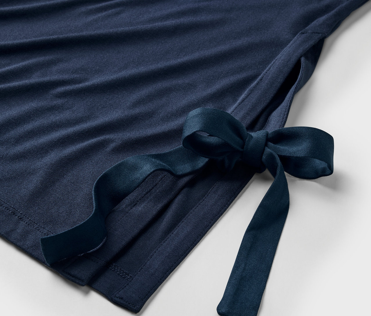 Detailansicht eines marineblauen Kleides mit Schleife an der Seite.