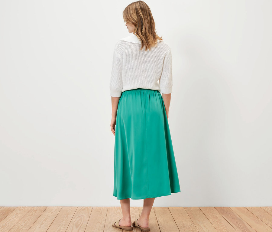 Frau von hinten stehend trägt einen Satinrock.