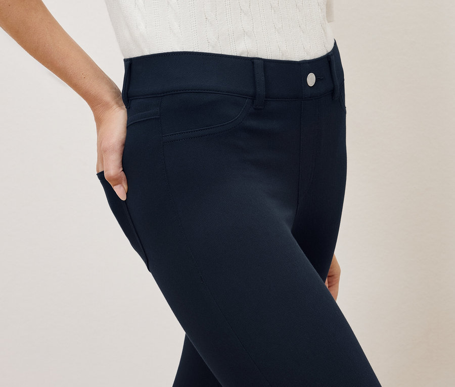 Frau hat Hand in der Tasche einer dunkelblauen Hose.