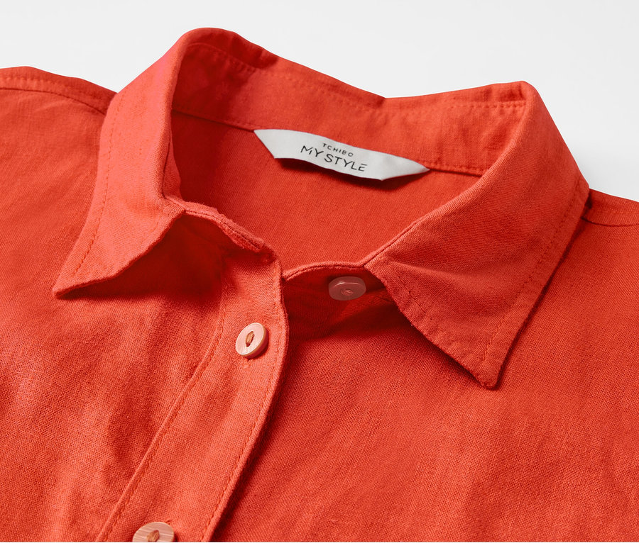 Detail einer orangefarbenen Leinenbluse.