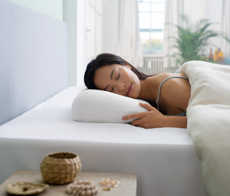 Frau schläft auf einem weißen Bett mit einem TEMPUR ONE® Support Schlafkissen.