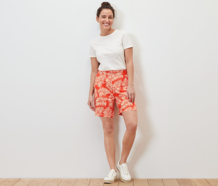 Eine Frau steht und trägt bedruckte Jerseyshorts und ein weißes T-Shirt.