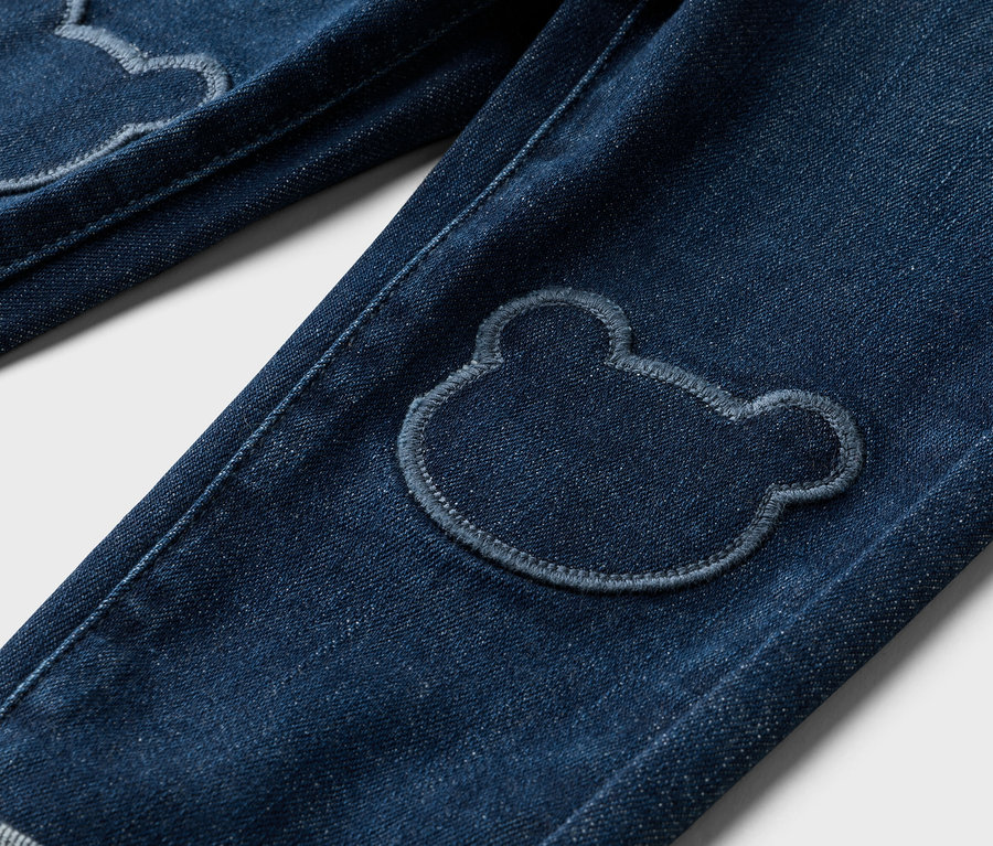 Nahaufnahme von Jeans mit Bärenflicken auf den Knien.