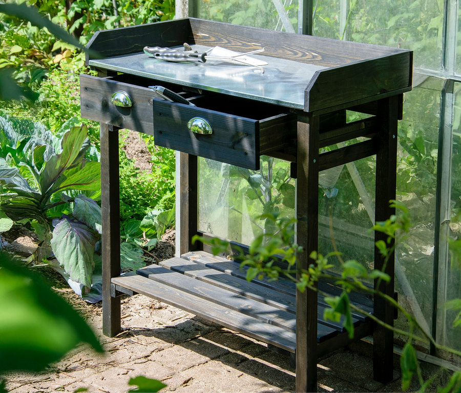 Ein schwarzer Pflanztisch mit Schubladen steht im Garten.