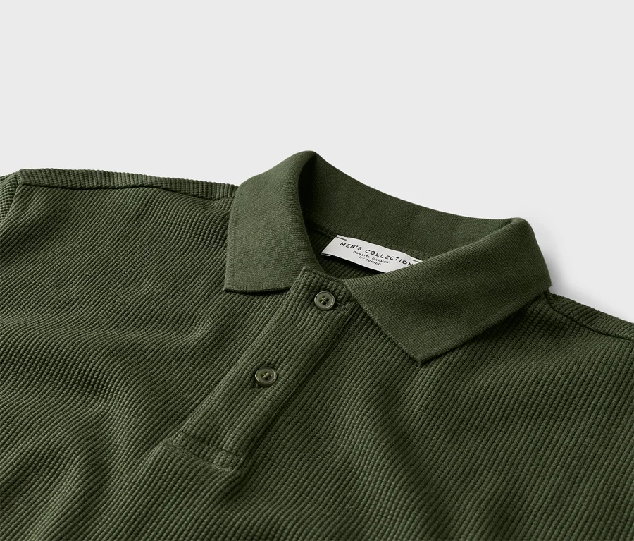 Nahaufnahme eines olivgrünen Poloshirts mit zwei Knöpfen und Kragen.