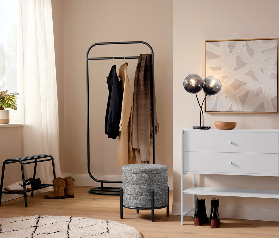 Flur mit einer Tischleuchte mit Schirmen aus Rauchglas, einem Indoorteppich »NOMAD Rhombus Line« und einer Garderobe.