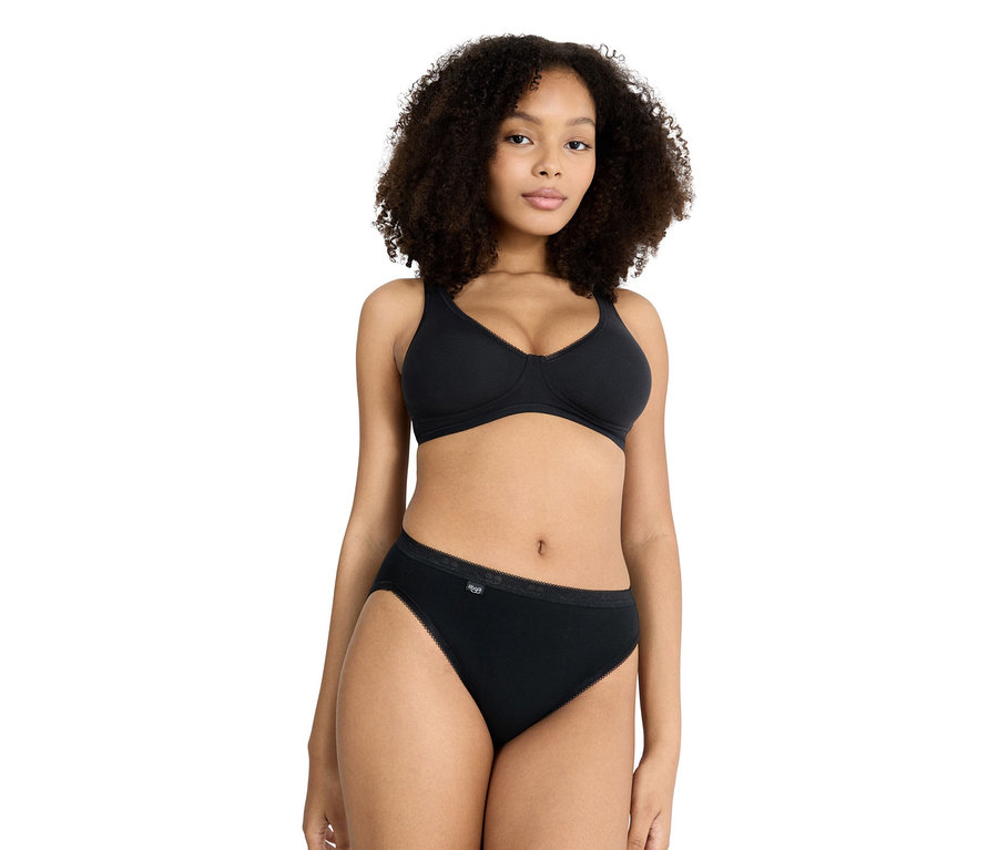 Frau mit lockigem Haar, die einen schwarzen BH und eine schwarze Unterhose trägt.