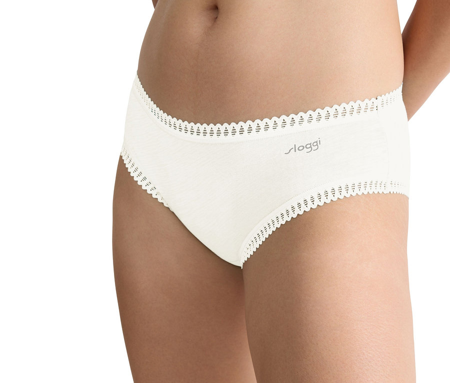 Nahaufnahme einer Person, die einen beigen Sloggi-Slip mit Spitzenbesatz trägt.