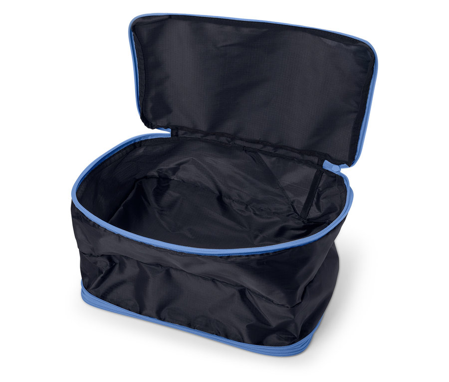 Offene, leere, schwarze Reisetasche mit blauem Reißverschluss auf weißem Hintergrund.