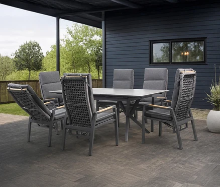 Sechs graue Stühle stehen um einen grauen Tisch auf einer Terrasse.