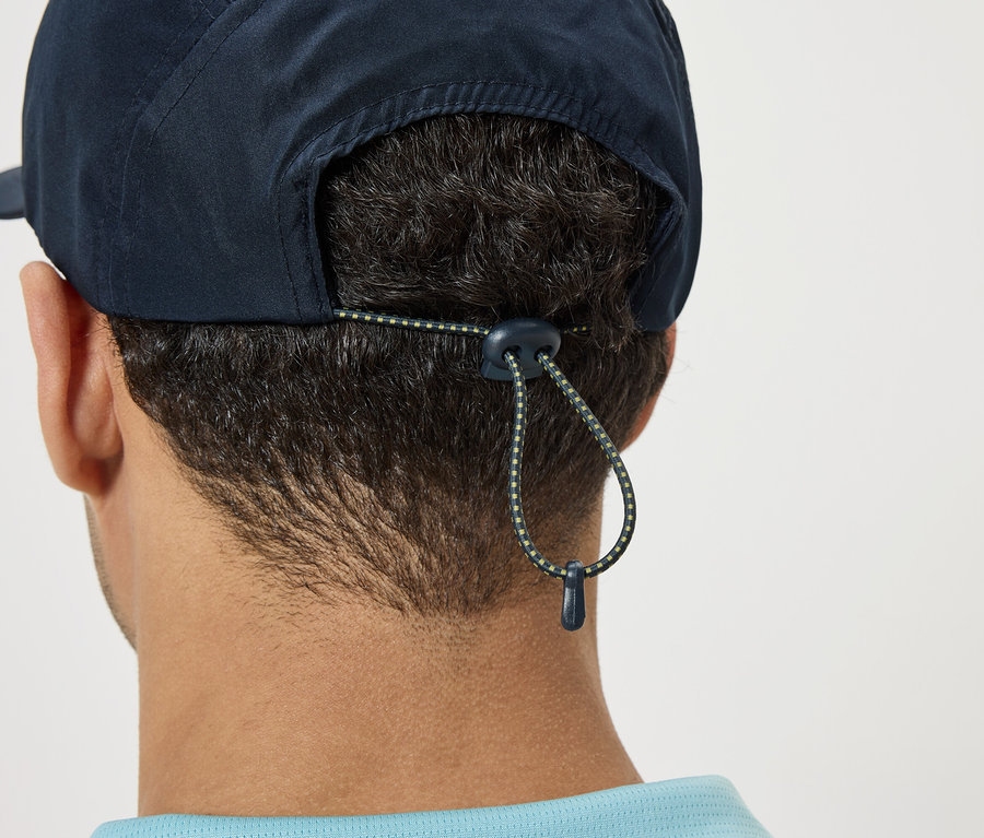 Nahaufnahme der Rückseite des Kopfes einer Person, die eine marineblaue Kappe mit verstellbarem Kordelzug trägt.