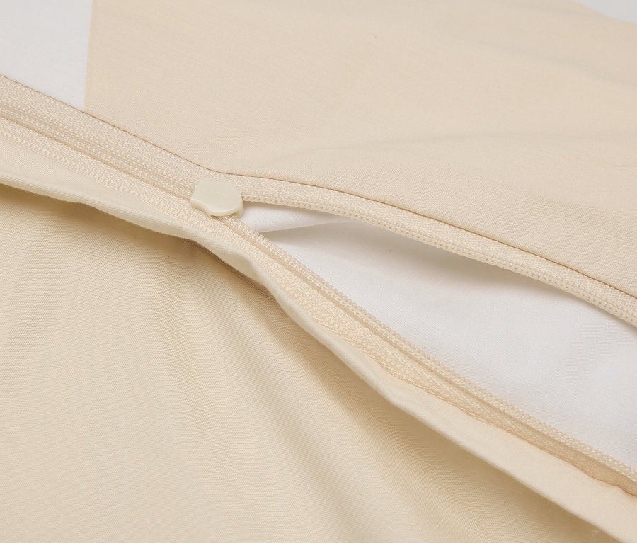 Nahaufnahme eines teilweise geöffneten, cremefarbenen Bettbezugs mit Reißverschluss.