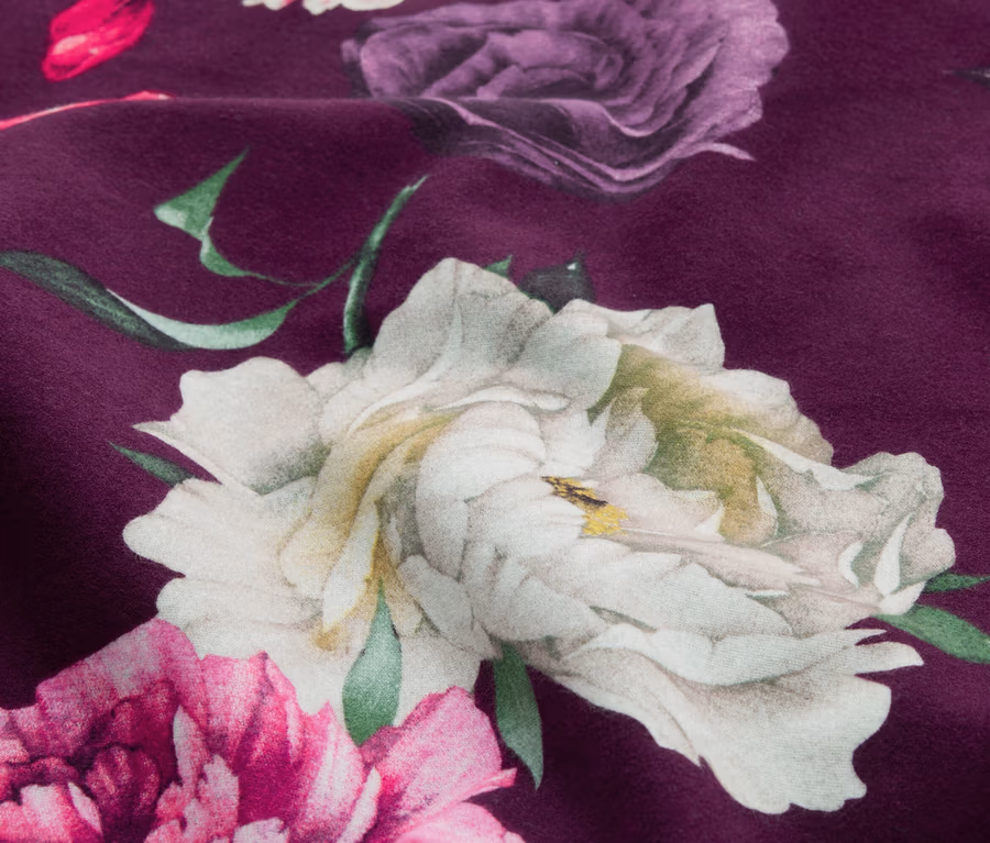 Dunkelvioletter Stoff mit großem Blumenmuster in Weiß, Lila und Pink, mit grünen Blättern.