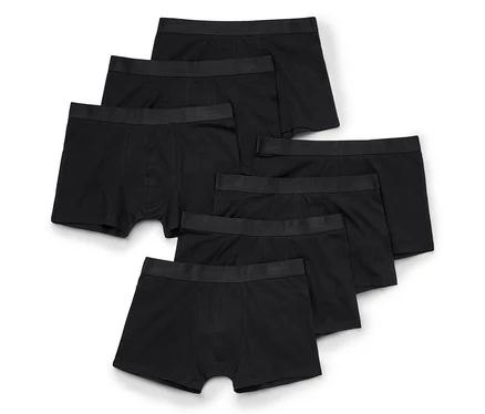 Sechs schwarze Boxershorts mit schwarzem Gummibund, fächerförmig auf weißem Hintergrund ausgebreitet.