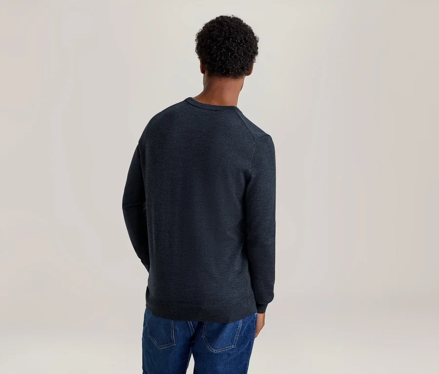 Person von hinten, trägt dunkelblauen Langarmpullover und blaue Jeans.