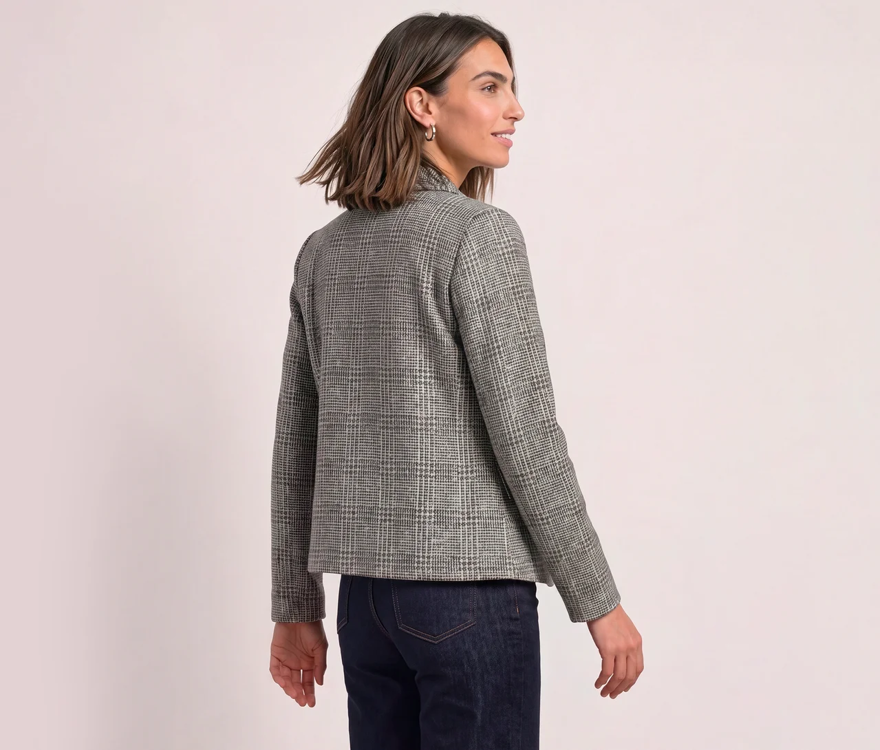 Frau von hinten, leicht nach rechts gedreht, trägt einen karierten Street One Blazer und dunkle Jeans.