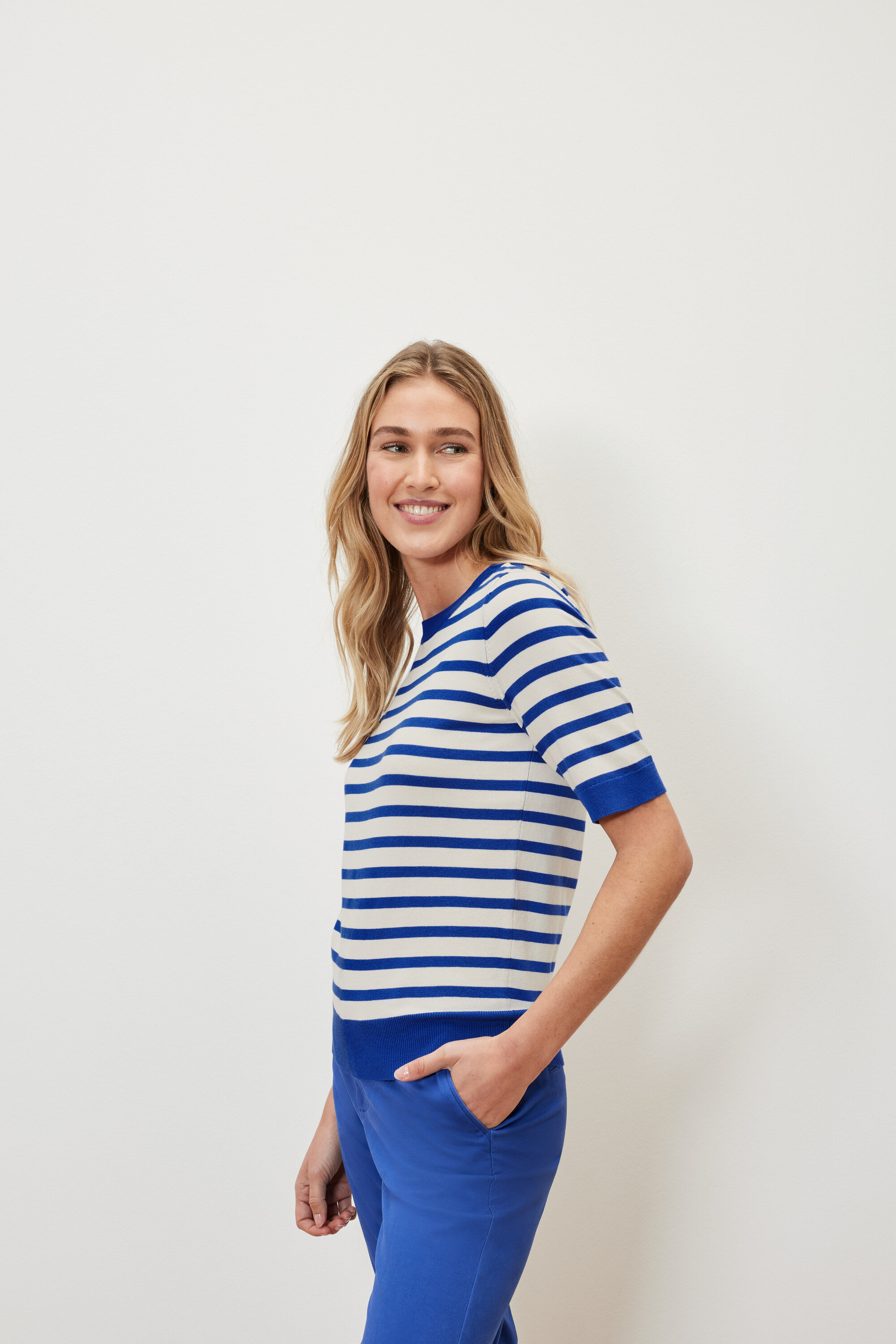 Frau trägt einen gestreiften Feinstrickpullover und blaue Hosen.