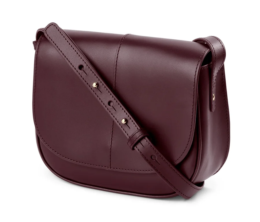 Detailaufnahme einer bordeauxroten Lederhandtasche »Saddle Bag« mit verstellbarem Riemen.