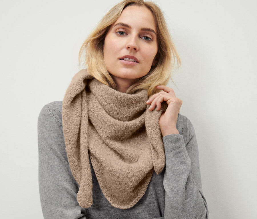 Blonde Frau trägt Dreiecksschal in Bouclé-Optik.