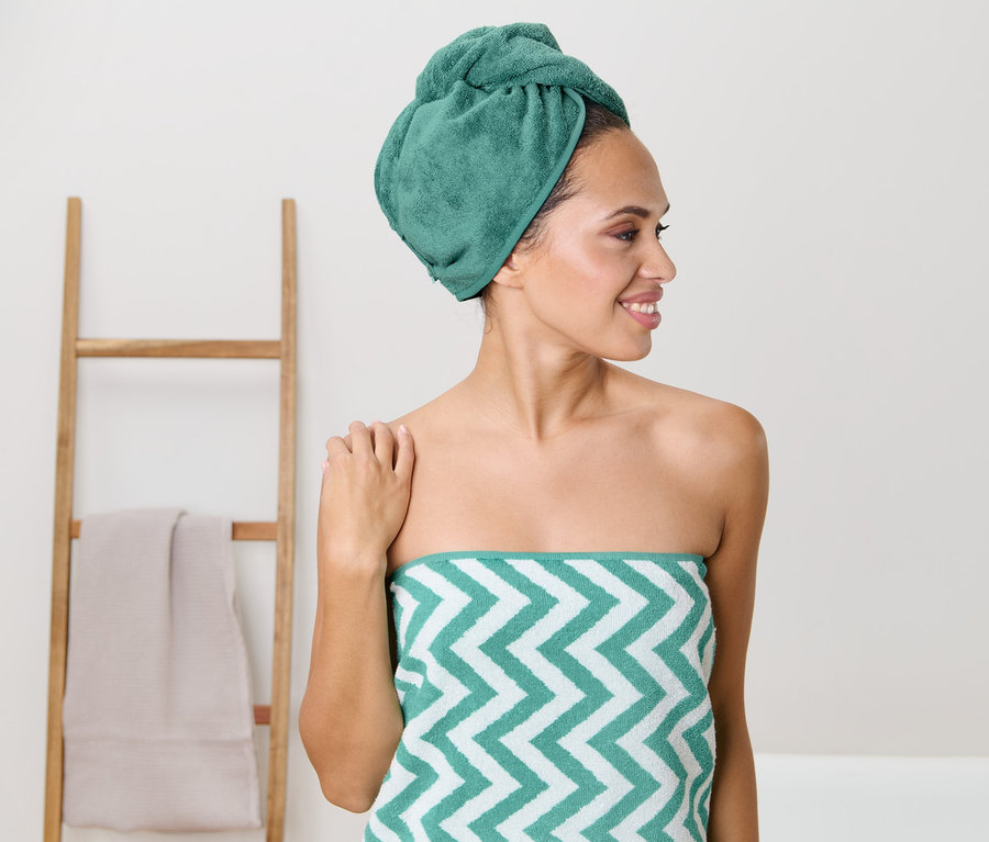 Frau mit Turban-Handtuch, aqua, auf dem Kopf und einem Fischgrätmuster-Handtuch um den Körper gewickelt.
