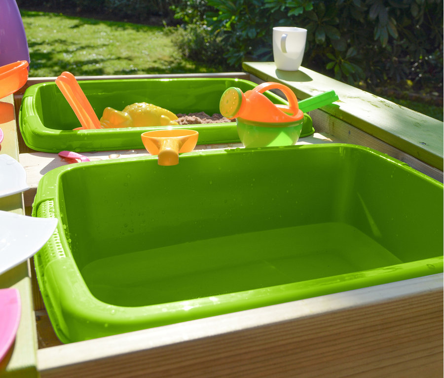 Grüner Wendi Picknick- und Matschtisch mit Bänken mit Sand, Spielzeug und Gießkanne.