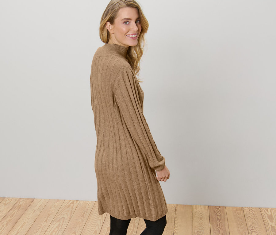 Frau posiert in einem gerippten Strickkleid mit Stehkragen.