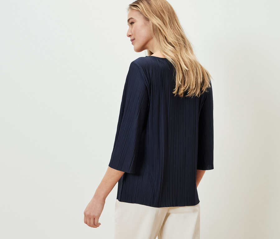 Frau trägt ein Plissee-Blusenshirt.