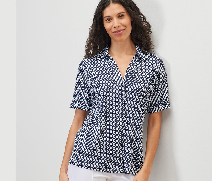 Frau trägt ein bedrucktes Blusenshirt mit Knopfleiste.