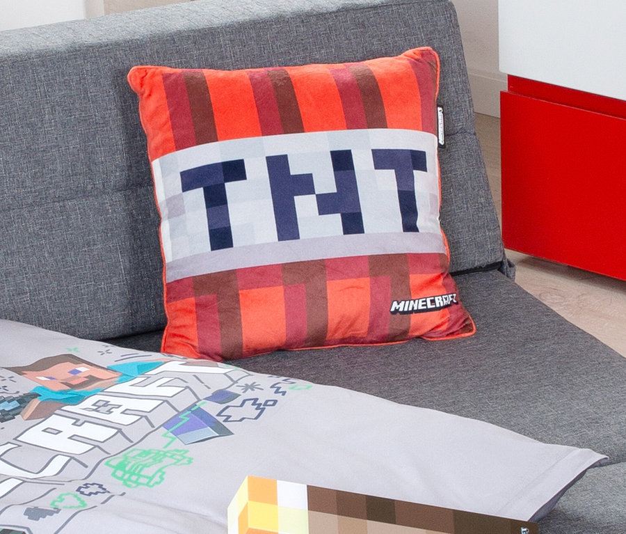Auf einem grauen Sofa liegt ein Minecraft TNT Dekokissen und Minecraft Bettwäsche.