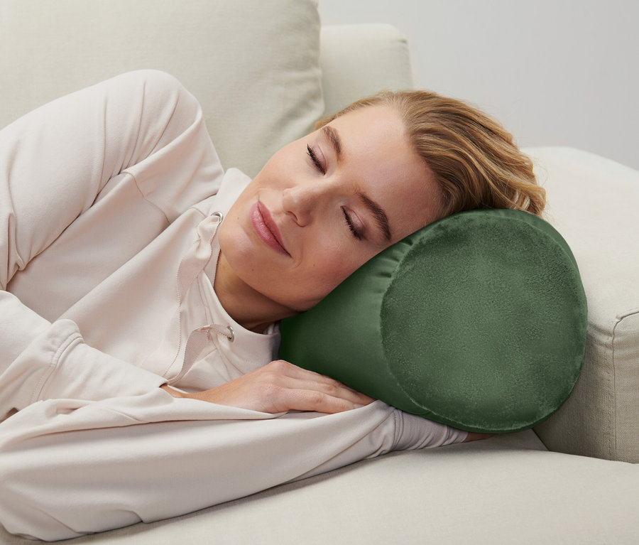 Frau schläft auf einer Couch mit einem zylinderförmigen Kissen unter ihrem Kopf.