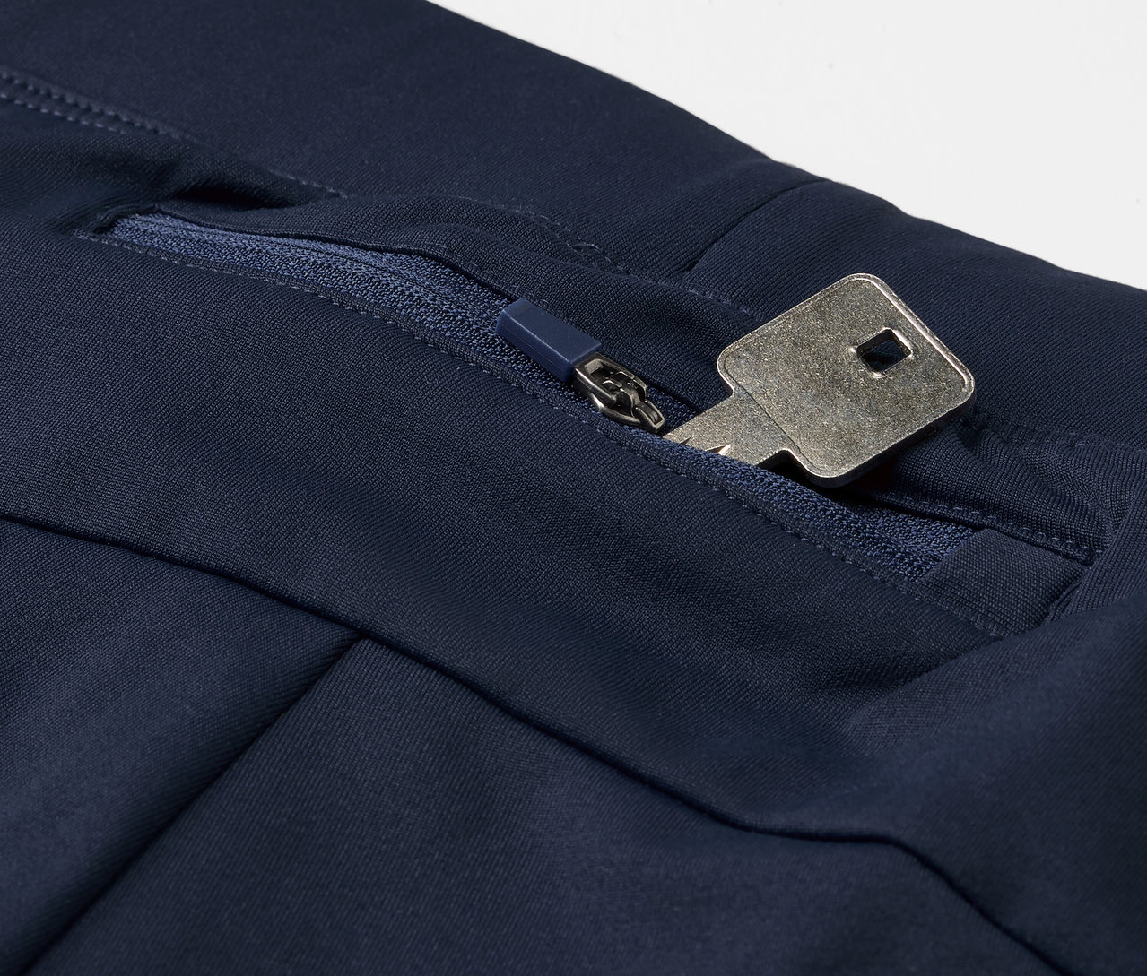 Detail einer blauen Windprotection-Lauftight mit einem Schlüssel in der Reissverschlusstasche.