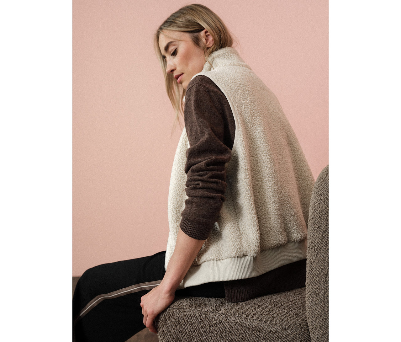 Frau sitzt und trägt eine Street One Teddyweste über einem braunen Pullover.