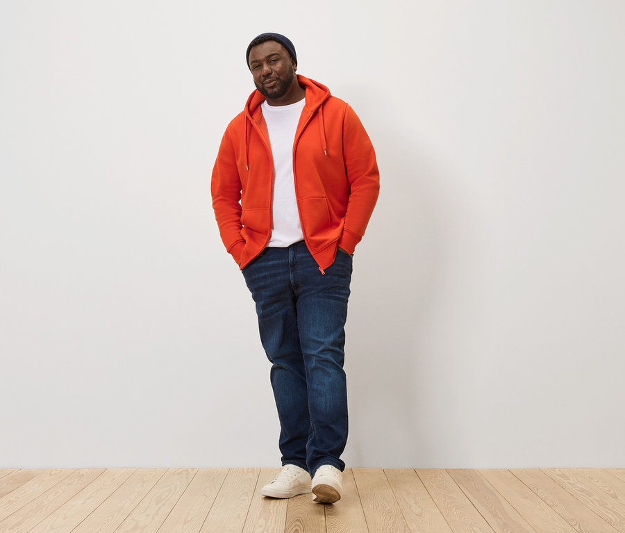 Mann posiert in orangefarbener Kapuzenjacke.