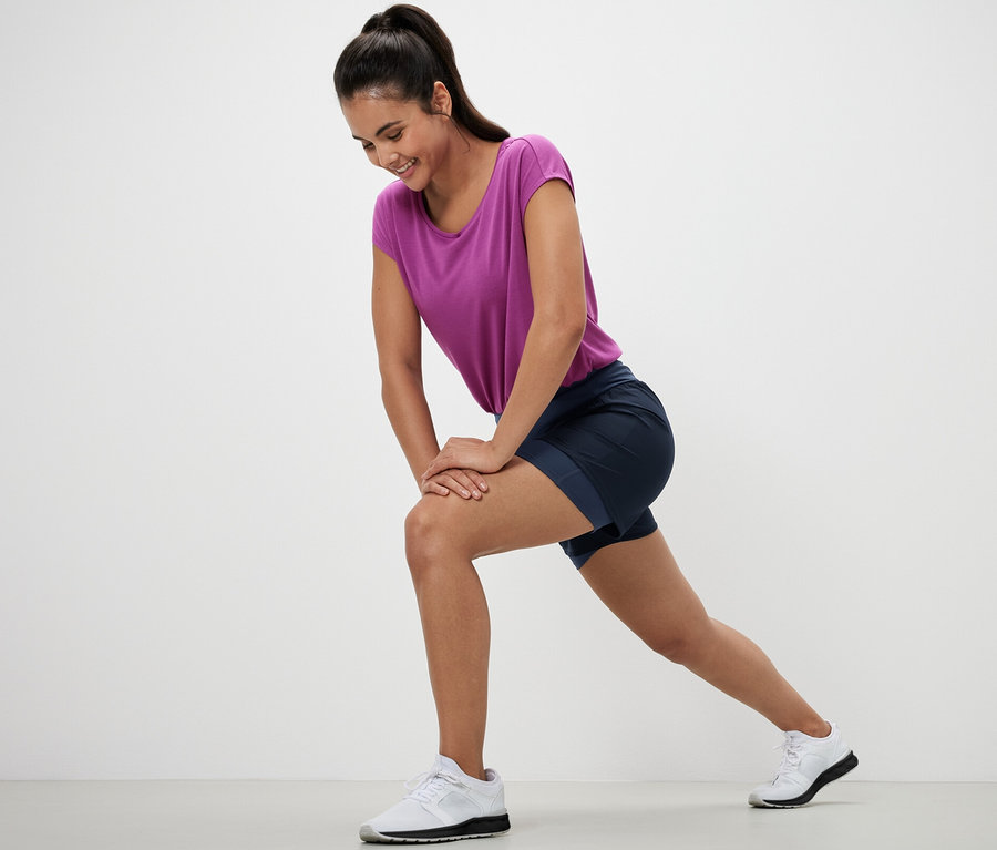 Frau dehnt sich in 2-in-1-Laufshorts.