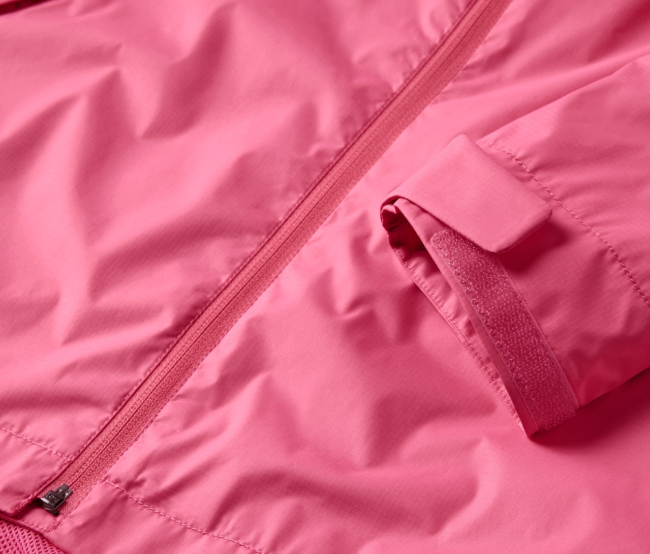 Detailansicht einer pinken Regenjacke mit Reißverschluss und Ärmel.