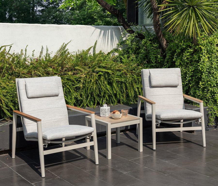 Zwei hellgraue ScanCom Outdoor-Loungesessel mit verstellbarer Rückenlehne und ein Tisch mit Erfrischungen auf einer Terrasse.