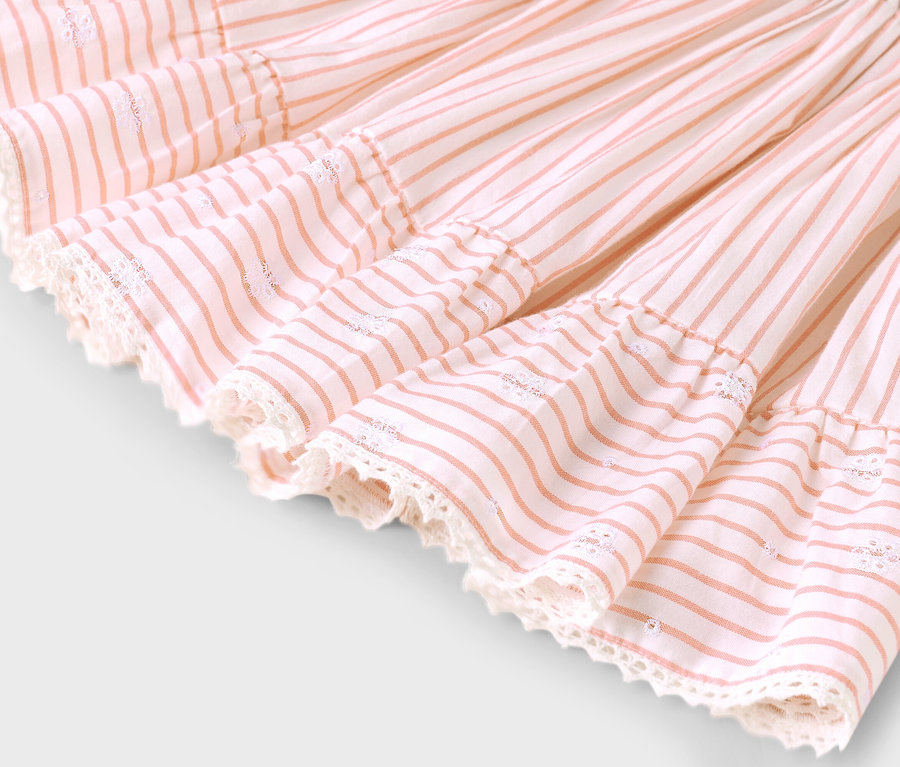 Nahaufnahme eines Rocksaums mit rosa Streifen und Spitzenbesatz.