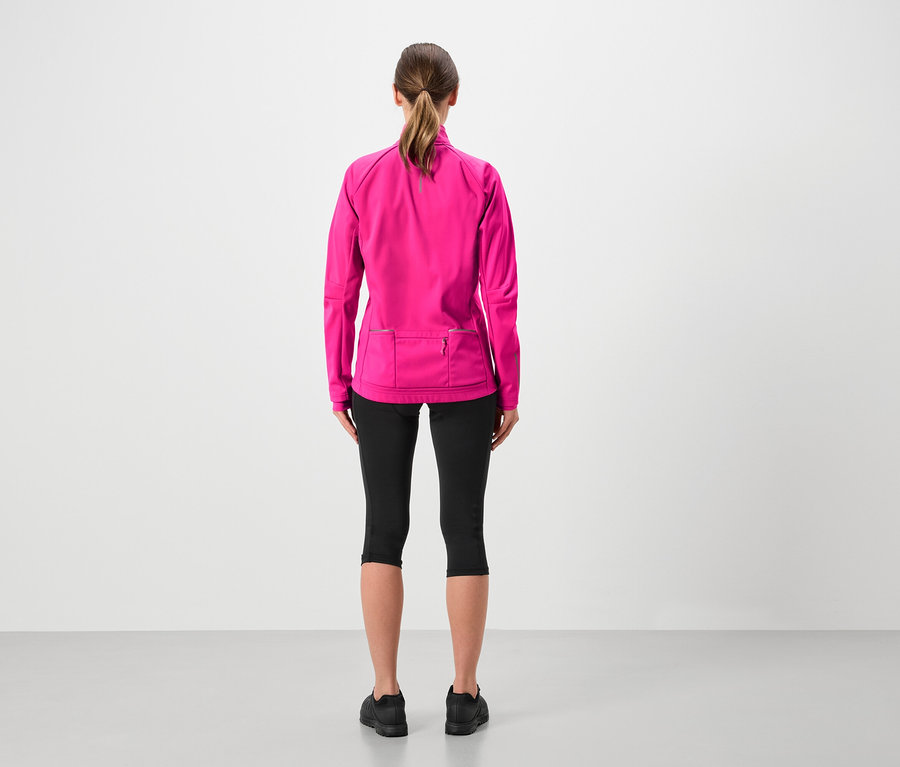 Rückansicht einer Frau mit Pferdeschwanz, die eine pinkfarbene Jacke, schwarze Leggings und schwarze Schuhe trägt.