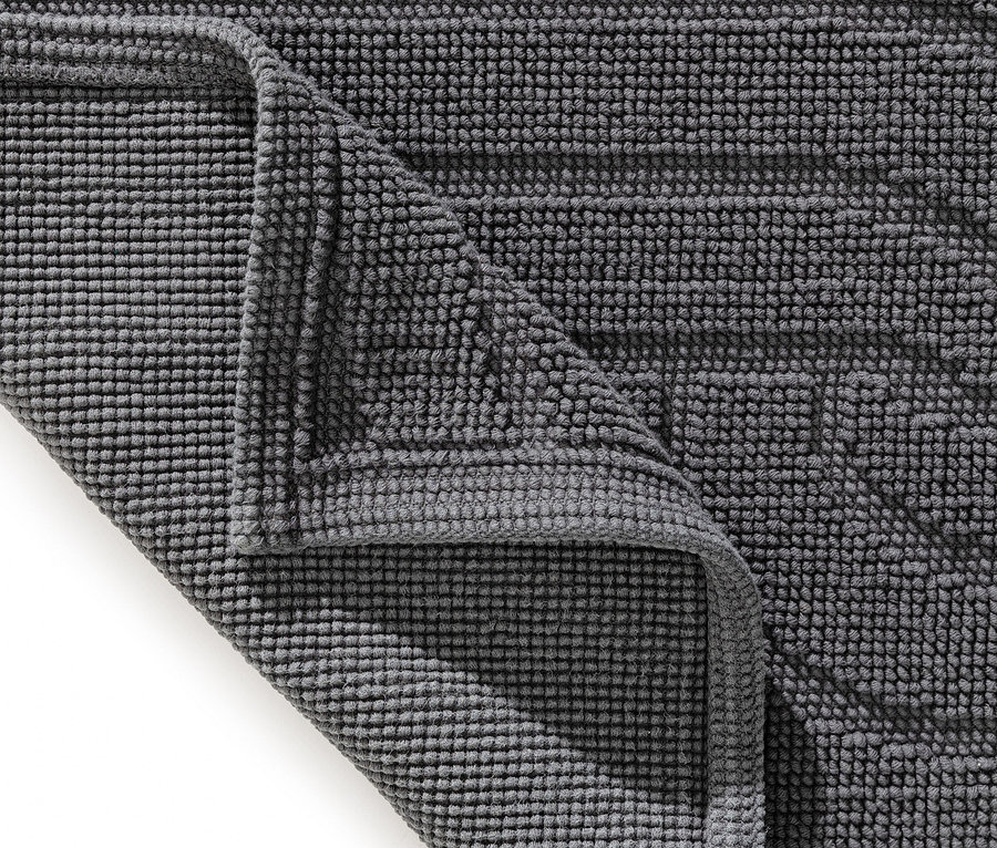 Nahaufnahme einer grauen Badematte mit Noppenstruktur, deren Ecke umgeschlagen ist.