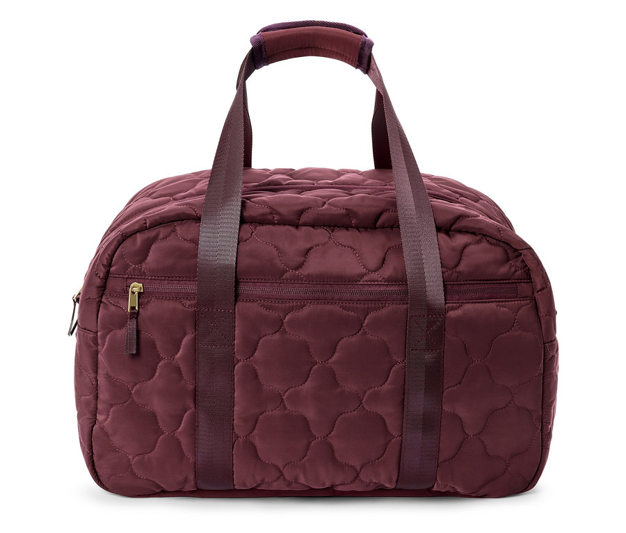 Nahaufnahme einer gesteppten, bordeauxroten Reisetasche mit Griffen und einem Reißverschlussfach.