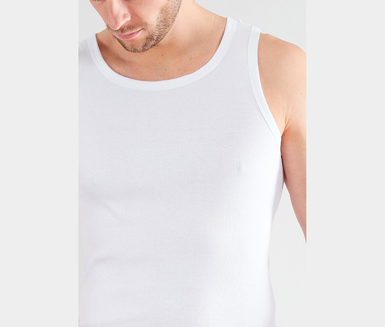 Nahaufnahme eines Mannes mit Bart, der ein geripptes, weißes Tanktop trägt.