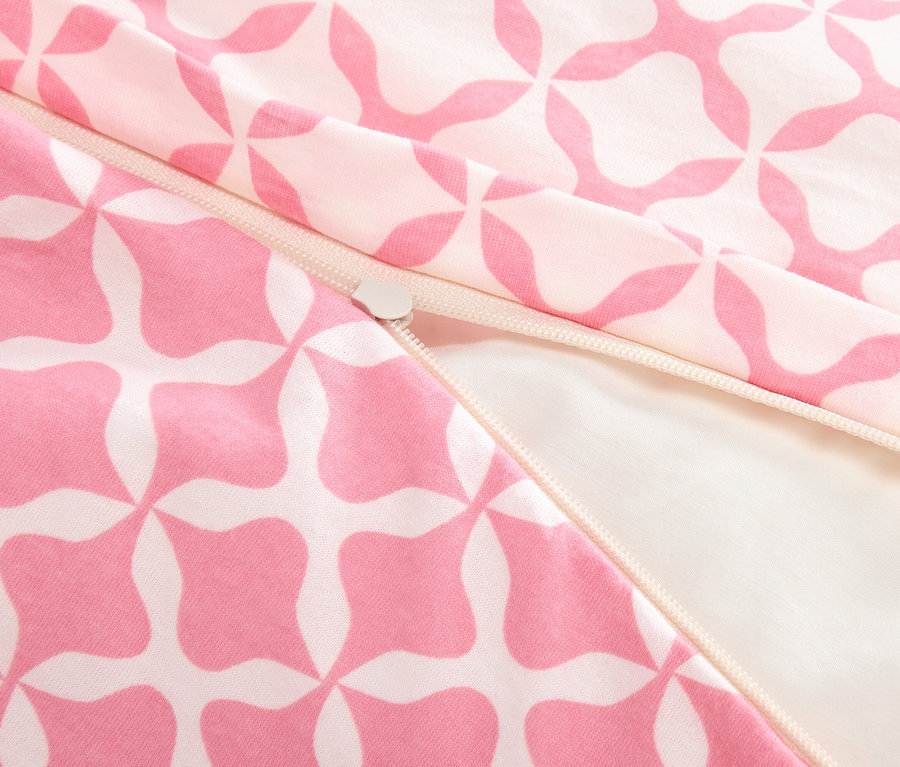 Nahaufnahme eines teilweise geöffneten Reißverschlusses auf einem rosa-weiß gemusterten Stoff.