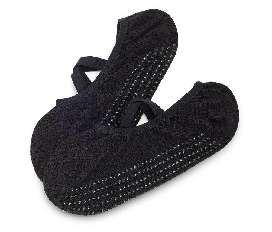 Zwei schwarze Socken mit Riemen und Noppen liegen übereinander auf einem weißen Hintergrund.