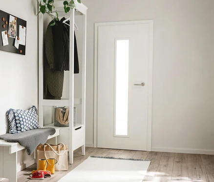 Heller Eingangsbereich mit weißer Bank, Garderobe mit Jacken und schwarzer Magnettafel. Auf dem Holzboden führt ein hellfarbener benuta Läufer »Mia« zu einer weißen Tür.